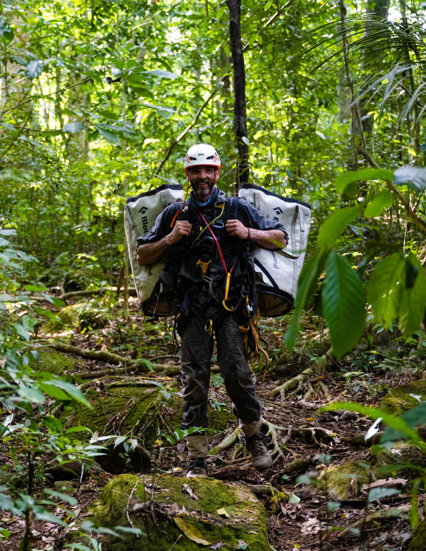 Ollie Laker of Figure Nine carrying climbing equipment through the forest.